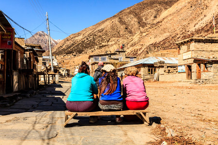 Manang, Nepal - November 11, 2015: Three nepalese women sitting on the bench in the street in the mountain village Manang, Himalayaのeditorial素材