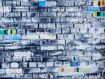 Rough white painted brick wall with colored bricks, textured background