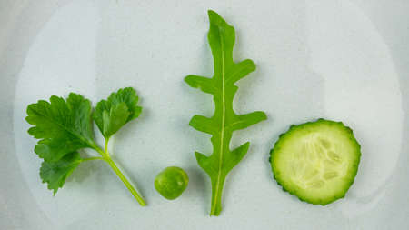 Plate with one pea, lettuce, cucumber slice and parsley. Diet to lose weighの写真素材