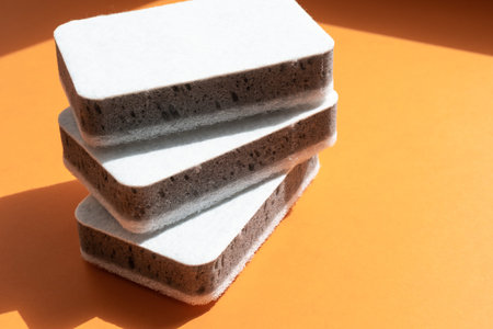 Three grey kitchen sponges on the orange background, cleaning conceptの写真素材