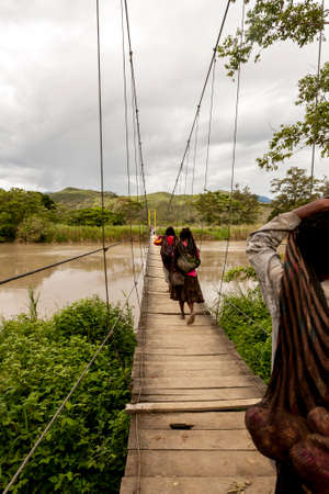 Three local Dani women bear the load across the bridge, Papua New Guinea.の写真素材