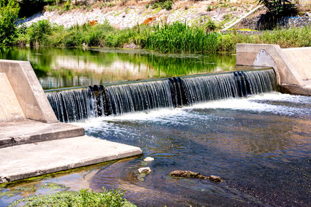 Water cascade streaming down from small dam, water saving ecology concept.