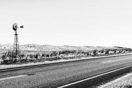 Windmill near empty asphalt road through Australian outback. Northern Australiaの写真素材