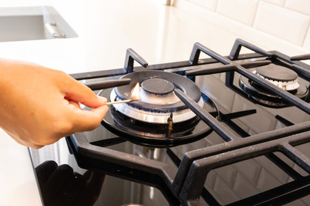 Female hand with a match ignites a gas burner