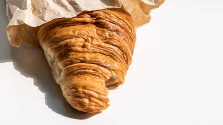 Tasty fresh croissant in the brown craft packet, junk food conceptの写真素材