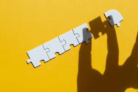 Shadow of hand with the piece of jigsaw puzzle to complete the line. Concept of successの写真素材