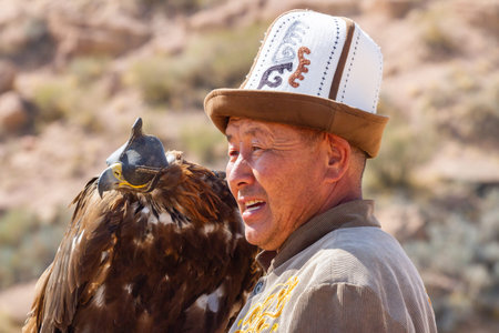 Tosor, Kyrgyzstan - October 1, 2022: Kyrgyz hunter or Berkutchi hugging a golden eagle, Kyrgyzstan.