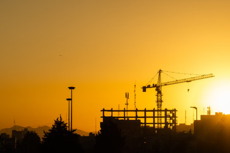 Industrial background with silhouette of construction crane at sunsetの写真素材