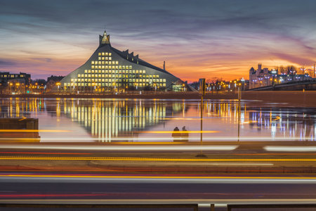 Picturesque view on the modern architecture of Latvian national library over the river with colorful sky in background. Lights creating reflections in river.のeditorial素材