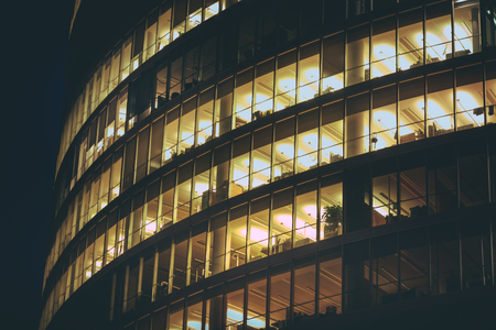 Modern office building made from glass at night time. Lights in the office windows. Modern architecture skyscraper.