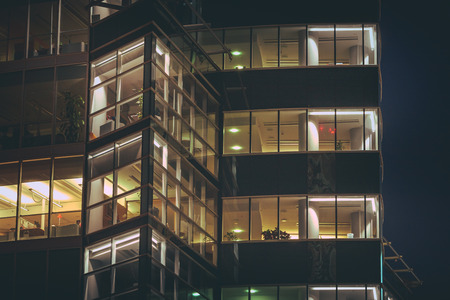 Modern office building made from glass at night time. Lights in the office windows. Modern architecture skyscraper.のeditorial素材
