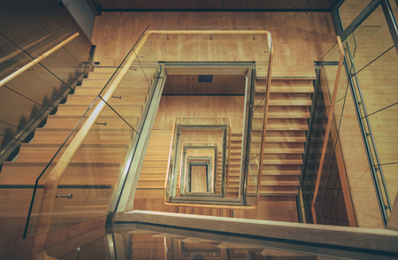 Spiral staircase from above with parquette floor. Square shaped stairs going downwards creating layers from each floor.のeditorial素材