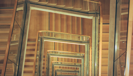 Spiral staircase from above with parquette floor. Square shaped stairs going downwards creating layers from each floor.のeditorial素材