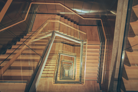 Spiral staircase from above with parquette floor. Square shaped stairs going downwards creating layers from each floor.のeditorial素材