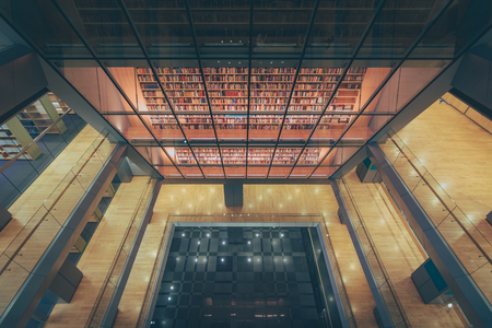 Huge bookshelf with tons of colorful books behind a glass wall. Collection of books in National library of Latvia. Modern architectural masterpiece.のeditorial素材