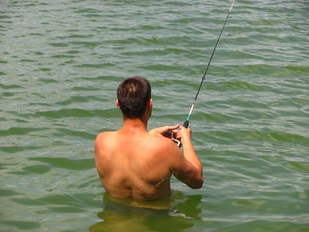 fisherman catches a fish in waterの写真素材