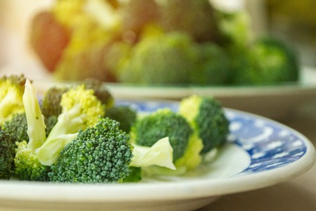 inflorescences of green fresh cabbage of broccoli close up on a plate, small depth of field. sunlight in the photoの写真素材