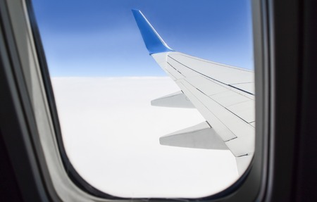 View from porthole on the wing and the clouds under the wing of an airplaneの写真素材