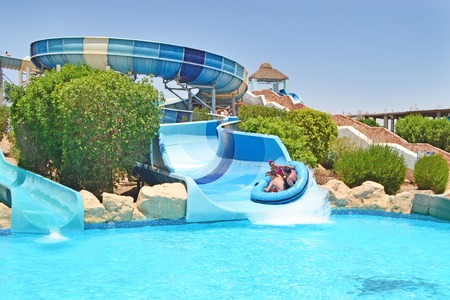 Hurghada, Egypt - May 16th 2018: friends riding down on water slide at aqua park. Summer resort concept.のeditorial素材