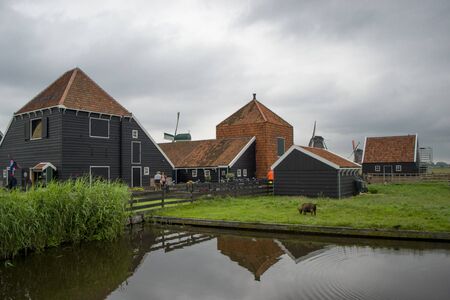 Amsterdam, Netherlands - 5th June, 2019: Zanse Schans is an open-air museum in Netherlands, near of Zaandam. Wooden houses under red roofs, cloudy weather and fresh green grass.のeditorial素材