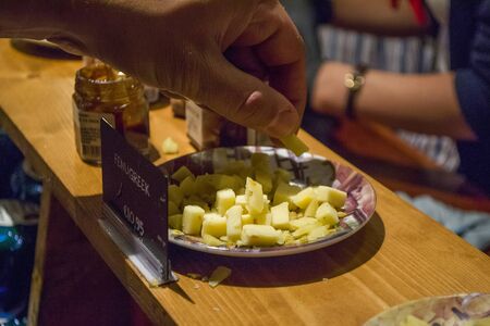 Zaanse Schans, Netherlands - 5th June, 2019: Tourists are tasting Dutch fermer cheese in the showroom of an old cheese factory in Zaandam, Zaans Schans. Close up view of the man s hand and cheese.のeditorial素材