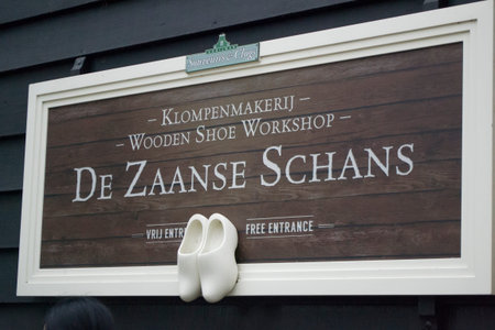 Zaanse Schans, Netherlands - 5th June, 2019: Sign with the inscription on the wall of the workshop for the manufacture of wooden Dutch shoes klompen. Ceramic small clogs hung up under the inscription.のeditorial素材