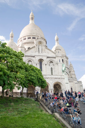 Paris, France - 6th June, 2019: The Basilica of the Sacred Heart of Paris, commonly known as Sacre -Coeur Basilica. Catholic temple on the butte Montmantre. Lots of tourists is on the stairs. Vertical.のeditorial素材