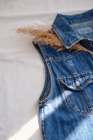 Blue denim overalls and dried flowers on a white background, top viewの写真素材