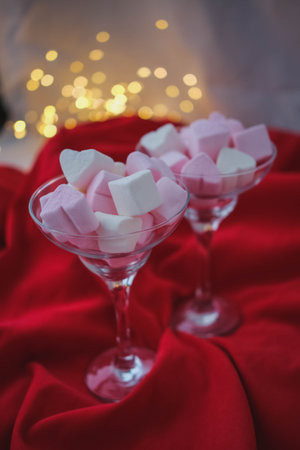 White and pink marshmallows in a glass on a red background