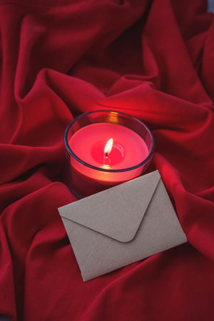 Candle and envelope on red satin cloth. Valentine's day concept.の写真素材