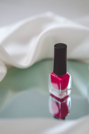 Red nail polish on white fabric background. Nail polish bottle.の写真素材