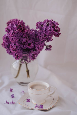 Lilac bouquet and cup of coffee on a white backgroundの写真素材