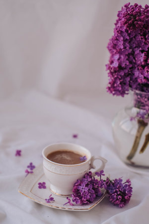 Cup of coffee and lilac flowers on a white background.の写真素材