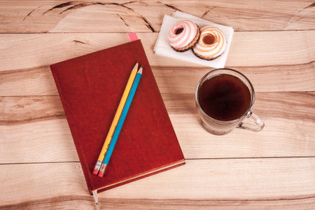 cup of espresso, checkered notebook and bun on wooden backgroundの写真素材
