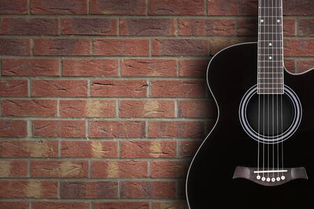 Black acoustic guitar on brick background with copy spaceの写真素材