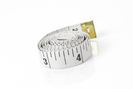 White tape measure rolled up on white inches