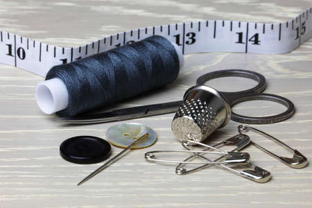 Supplies and equipment for sewing on a wood work surface cotton tape measure scissors thimble needle pins buttonsの写真素材