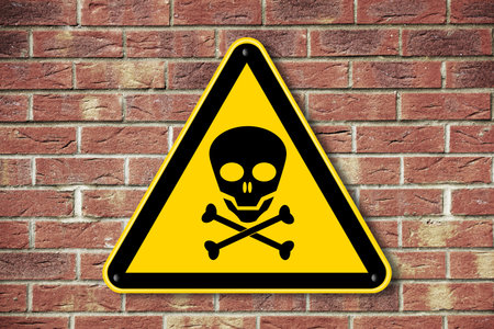 Skull and crossbones danger caution warning sign on a brick wall background