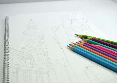 Pencil sketch of buildings on white paper lies with color pencilsの写真素材