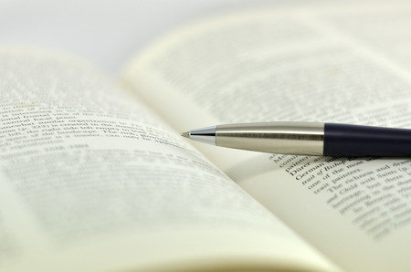 photograph of opened textbook with pen on white backgroundの写真素材