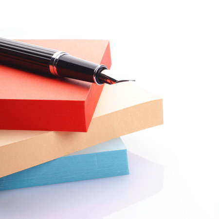 pen on a stack of colored notes on white background