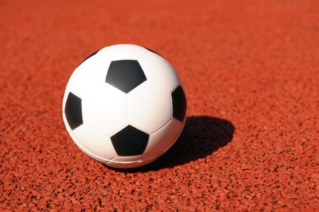 classic soccer ball on a red soccer fieldの写真素材