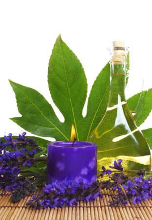 spa treatment with oil, candle and flowers on bamboo stickの写真素材