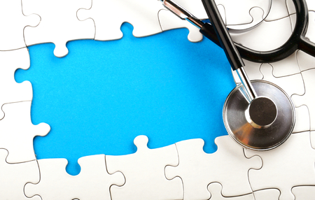 a stethoscope lying on an unfished puzzleの写真素材