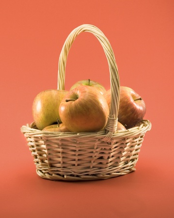 Basket full of apples on a red backgroundの写真素材