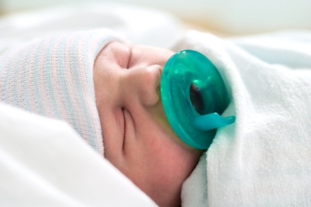 Newborn baby sleeping bundled in blankets with pacifierの写真素材