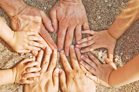 Family hands on sand beach. (two parents and two children hands)の写真素材