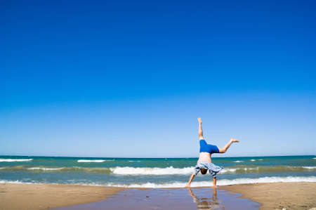 Happy man jumping over sea. Sand beach and blue water. Summer, vacation.の写真素材