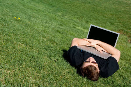 Man lying on the grass with laptop. 21st Century Lifestyle.の写真素材