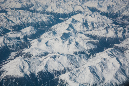 snowy mountain range from the plane with blue mountains